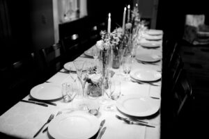 Elegant dukat middagsbord med tallrikar, glas, blommor och levande ljus