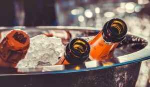 Två orange dryckesflaskor kyls i is i en metallbalja